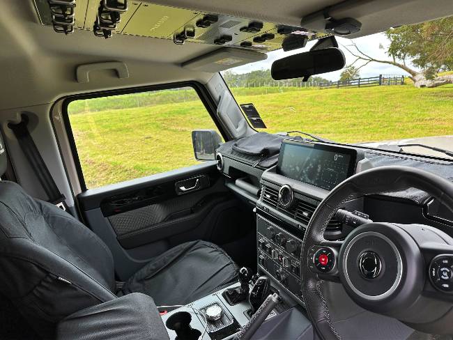 Ineos Grenadier interior with canvas seat covers, easy hose-down floor, and switches for Africa on the roof.